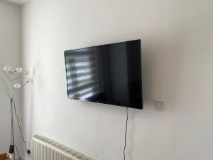 een flatscreen-tv aan een witte muur bij The London apartment in Londen