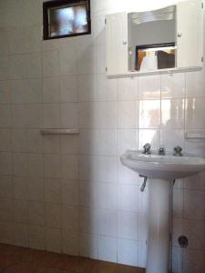 ein weißes Badezimmer mit einem Waschbecken und einem Spiegel in der Unterkunft Hotel 20 de Junio in Mina Clavero