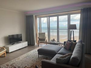 a living room with a couch and a flat screen tv at Appartement Belle Mer - Adults Only in Middelkerke