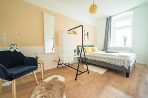 a bedroom with a bed and a chair and a mirror at FullHouse - Leonardo Apt - 3 Bedrooms & Balcony in Chemnitz
