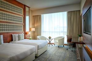 een hotelkamer met twee bedden en een groot raam bij dusitD2 Salwa Doha in Doha