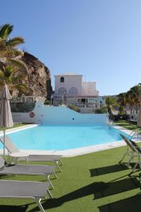 a large swimming pool with lounge chairs and palm trees at Canaima 308 in Puerto Rico de Gran Canaria
