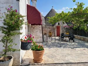 a patio with potted plants and a table and an umbrella at Masseria Gianca in Cisternino