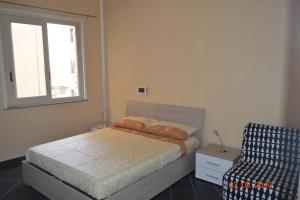 ein Schlafzimmer mit einem Bett, einem Fenster und einem Stuhl in der Unterkunft il veliero di naxos in Giardini-Naxos
