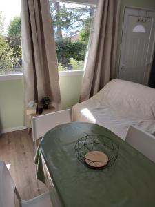 Cette chambre comprend une table verte, un lit et une fenêtre. dans l'établissement Studio J, à Oyonnax