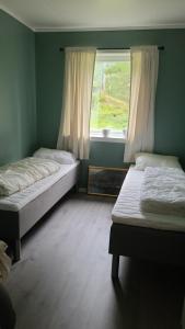 two beds in a room with a window at Lyngtun in Viksdalen