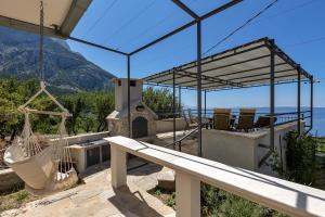 a house with a hammock and a view of the ocean at Cottage Baskovic in nature park in Makarska
