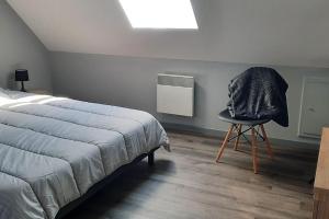 a bedroom with a bed and a chair and a window at La Maison LUDO in Arrest