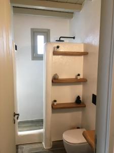 a bathroom with a toilet and wooden shelves at AGERI HOME in Koufonisia