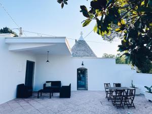 een patio met stoelen en een tafel voor een wit gebouw bij Trullo Assiolo in Valle d'Itria in Martina Franca