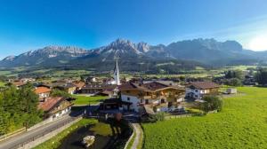 a village with a church and mountains in the background at Kaiserapart Steinadler - ELLMAU Zentrum in Ellmau