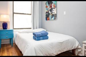 a bedroom with a bed with two blue towels on it at 4BR 10 mins walk to Central Park! in New York