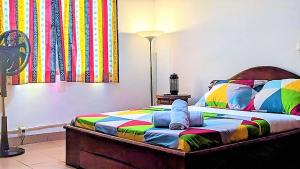 ein Schlafzimmer mit einem farbenfrohen Bett mit einer Lampe in der Unterkunft FIIAA in Jaunde
