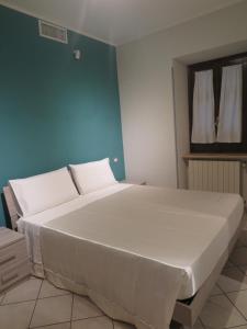 un grande letto bianco in una stanza con una parete blu di Appartamento QCM natura cultura e divertimento a Giulianello