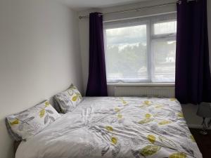 a bed in front of a window with a bedspread at London Heathrow Homes in New Bedfont