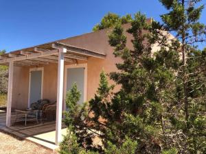 uma casa com um alpendre com uma mesa e uma cadeira em CAN FERNANDO - CASA CON PISCINA EN FORMENTERA em Cala Saona