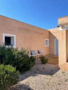 duas almofadas sentadas num banco em frente a um edifício em CAN FERNANDO - CASA CON PISCINA EN FORMENTERA em Cala Saona