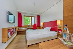 1 dormitorio con cama blanca y pared roja en Asam Hotel, en Straubing