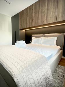 a bedroom with a large white bed with a headboard at 4friendscoresibrasov M&L in Braşov