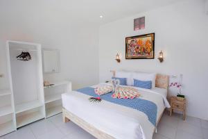 a bedroom with two beds and a picture on the wall at The Waterfront Beach House in Nusa Lembongan