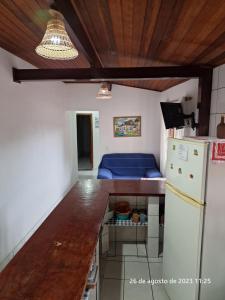 a kitchen with a refrigerator and a table and a couch at Casa em Ilhabela in Ilhabela