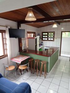 a kitchen with a counter with stools and a table at Casa em Ilhabela in Ilhabela