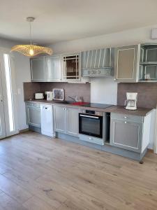 una cocina con armarios grises y electrodomésticos blancos en Gîte Cadet rousselle, en Lessay