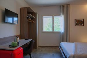 a hotel room with a bed and a desk and a window at Via Goito 25 Rooms & Apartment in Peschiera del Garda