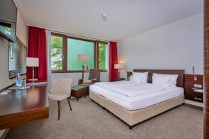 ein Schlafzimmer mit einem großen weißen Bett und einem Schreibtisch in der Unterkunft Asam Hotel in Straubing