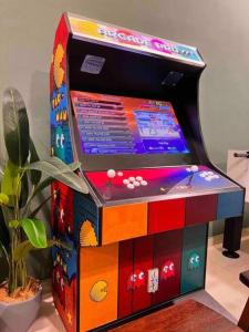 une machine de jeu vidéo colorée assise à côté d'une plante dans l'établissement Rusa Cottage (Sleeps 10 pax - 1 min walk from KSL), à Johor Bahru