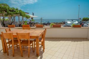 a wooden table and chairs with the ocean in the background at Incantevole villa sul mare in Torre San Giovanni Ugento