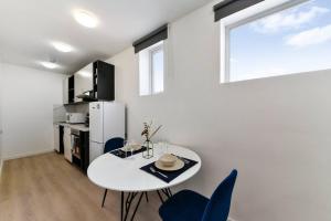 a white kitchen with a white table and blue chairs at Beautiful and Spacious 1 Bed Apartment in London