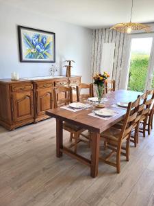 comedor con mesa de madera y sillas en Gîte Cadet rousselle, en Lessay