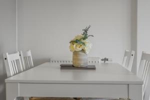 einen weißen Tisch mit einer Vase mit Blumen drauf in der Unterkunft Centrally Located Modern 2Bed 2Bath Apartment in London