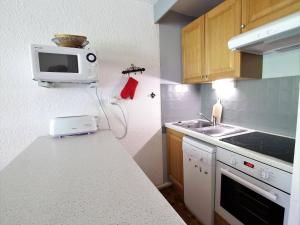 a kitchen with a counter with a microwave and a sink at Studio fonctionnel 4 pers, à 50m des pistes, proche commodités, piscine extérieure en été. - FR-1-330F-89 in Serre Chevalier +9 photos