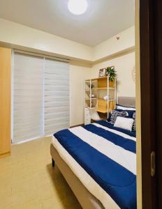a bedroom with a blue and white bed and a window at 4 Majestic View in Iloilo City