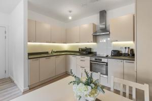 a kitchen with white cabinets and a vase of flowers at Centrally Located Modern 2Bed 2Bath Apartment in London