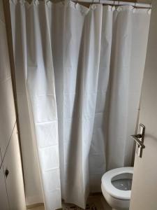 a bathroom with a toilet and a white shower curtain at Departamento Hipólito Irigoyen in Santa Fe