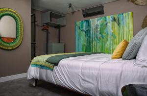 a bedroom with a bed with a painting on the wall at 1 On Royal in Cape Town