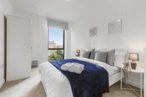 ein weißes Schlafzimmer mit einem weißen Bett und einem Fenster in der Unterkunft Centrally Located Modern 2Bed 2Bath Apartment in London