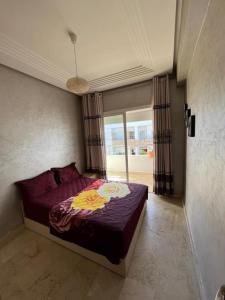 a bedroom with a bed with a purple comforter at apartment on the beach in El Harhoura