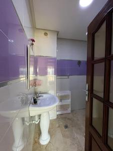 a bathroom with a white sink and purple walls at apartment on the beach in El Harhoura