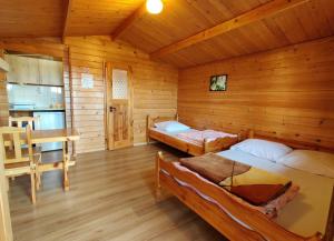 una camera con due letti in una baita di legno di PANORAMA Domki i Pokoje Nad Jeziorem 660-332-576 a Polańczyk