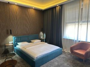 a bedroom with a blue bed and a chair at B&B Cvjetni in Zagreb