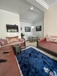 a living room with two couches and a blue rug at apartment on the beach in El Harhoura