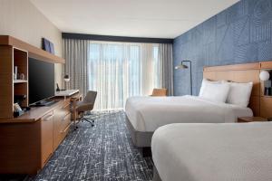 a hotel room with two beds and a television at Courtyard by Marriott Philadelphia South at The Navy Yard in Philadelphia