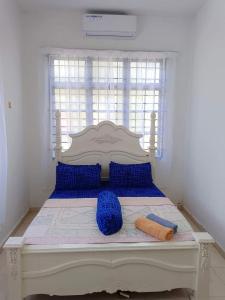 een slaapkamer met een bed met blauwe kussens en een raam bij Malin's Homestay Kota Bharu in Kota Bharu