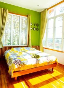 a bed in a room with green walls and windows at One&only homestay in Khao Kho
