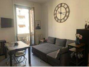 uma sala de estar com um sofá e um relógio na parede em Bilocale 5 min Stazione Centrale em Milão