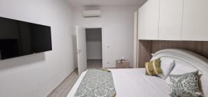 - une chambre avec un lit blanc et une télévision à écran plat dans l'établissement Orchidea, à Bologne